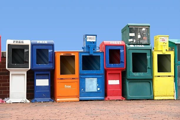 Row of colorful newspaper boxes, several marked “FREE,” standing empty