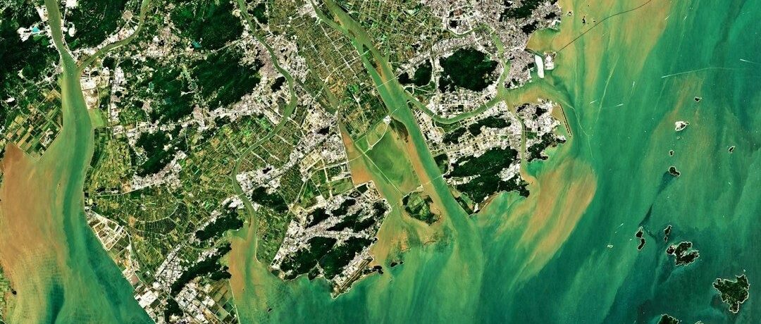Satellite view of coastal cities, waterways, islands, and surrounding sea