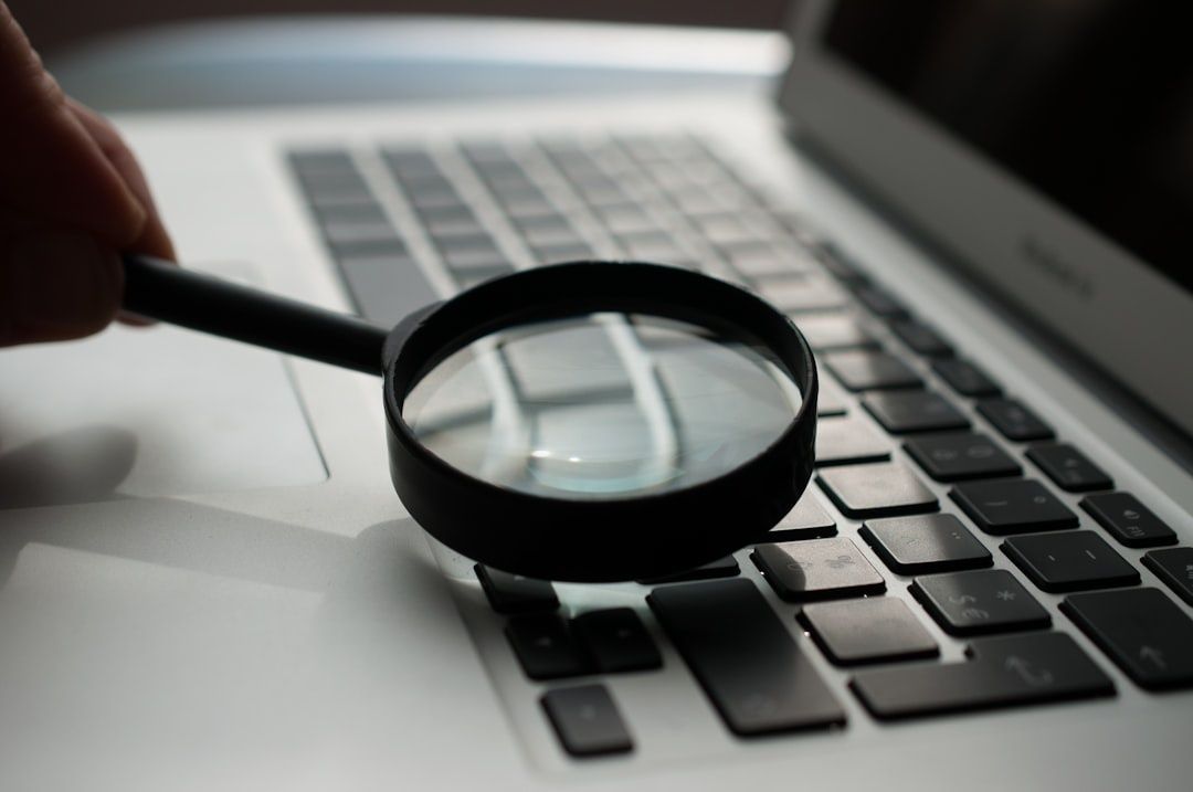Magnifying glass held over a laptop keyboard for digital investigation